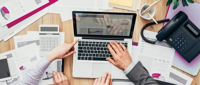 Business people working together, they are using a laptop and pointing at the screen, finance and accounting concept, top view